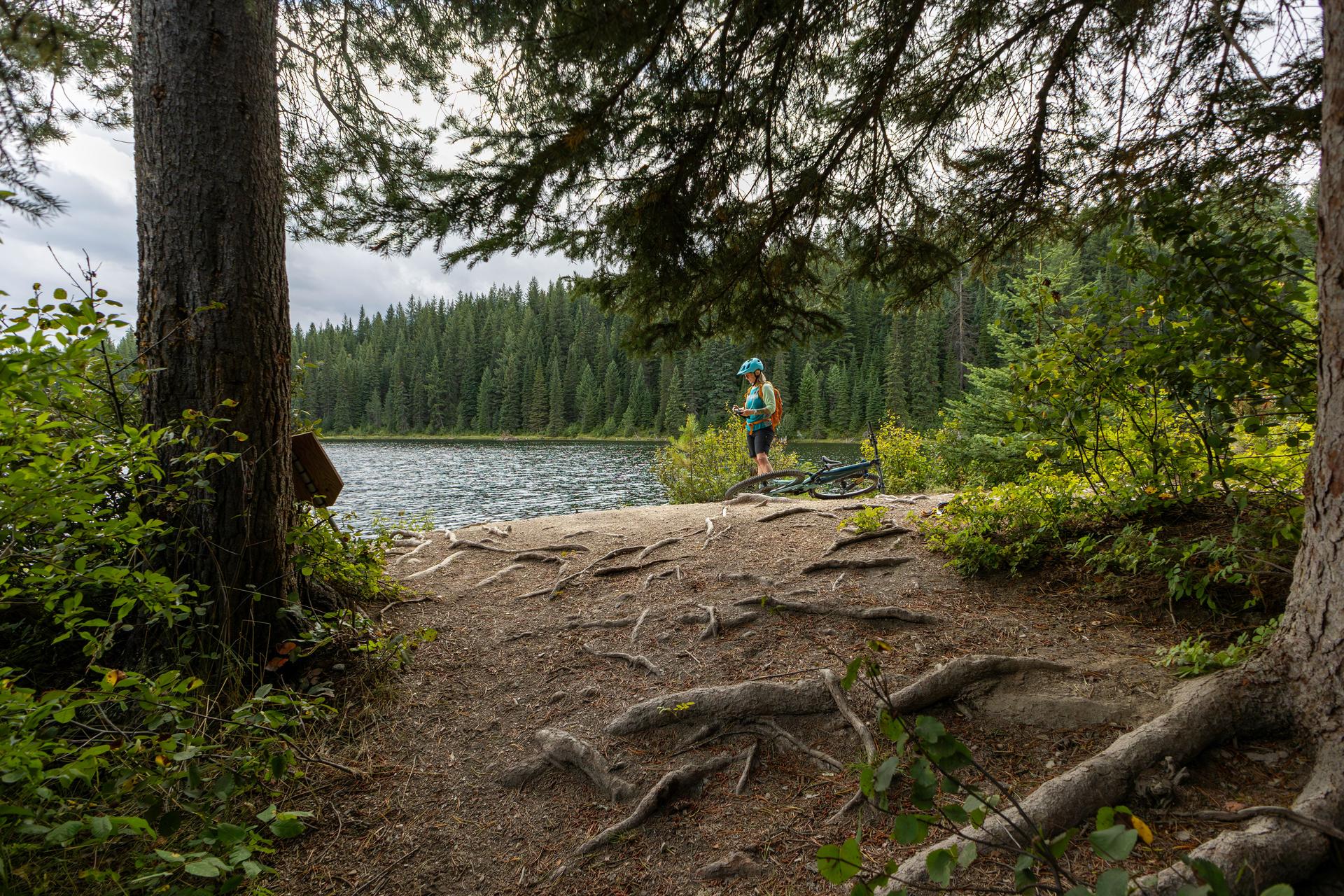 Woman mountain biker takes photo on lakeshore